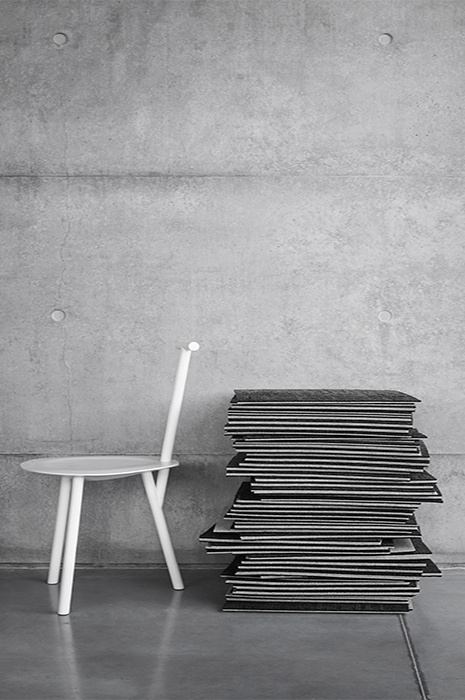 A pile of square carpet tiles resting against a chair